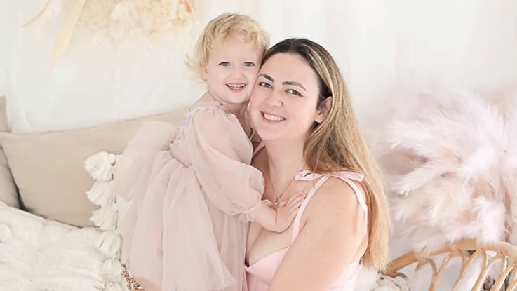 A mum and her daughter sitting on a bed
