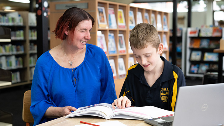 a mother reading with her son in a library