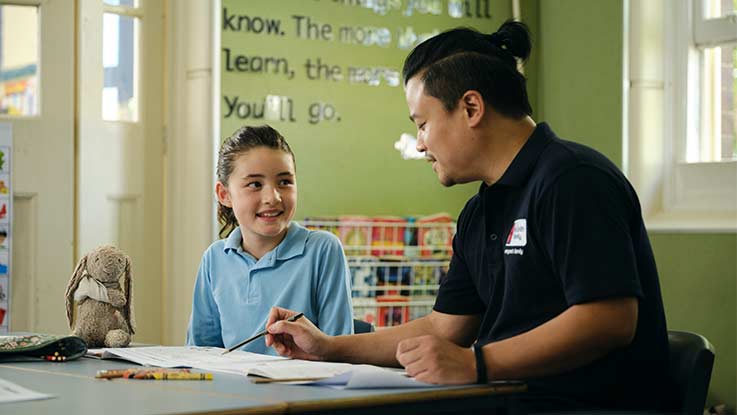 Lucy sitting with teacher in classroom