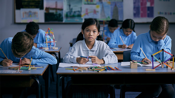 Girl looking at camera sitting at classroom desk