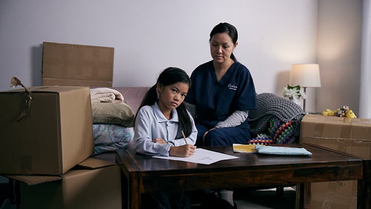 Girl and her mum sitting on couch surrounded by boxes