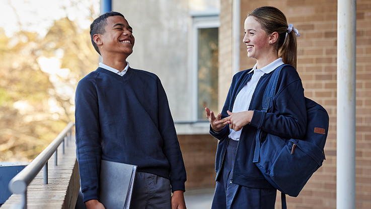 Students laughing in school hallway wearing school uniform