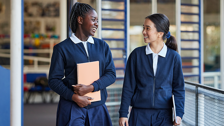 two high school student smiling at each other walking