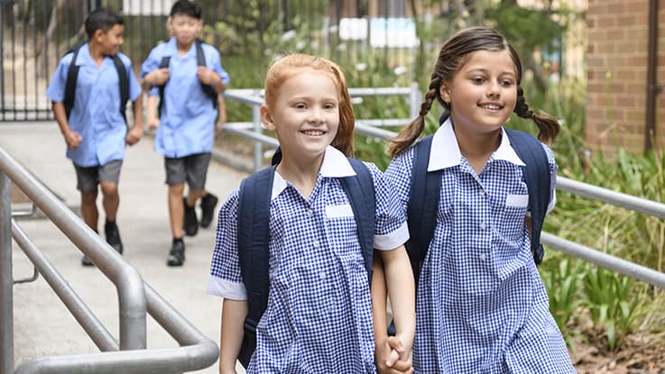 two primary school students holding hands and walking