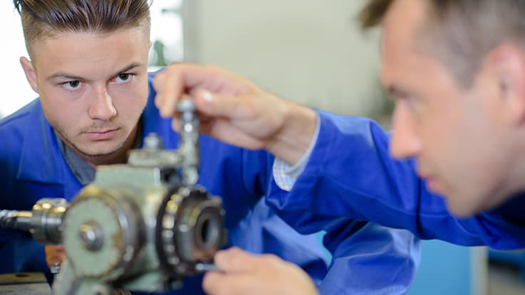 a student in blue overalls learns from a teacher