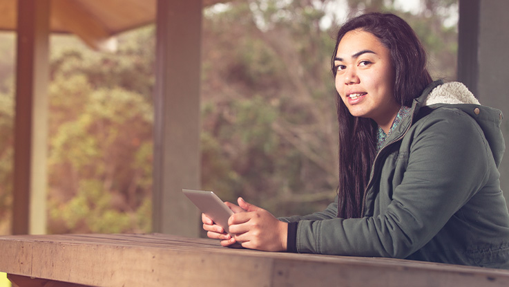 girl sitting at a park bench holding a phone