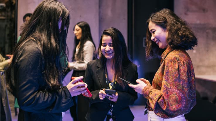 3 girls looking at their phones laughing and smiling