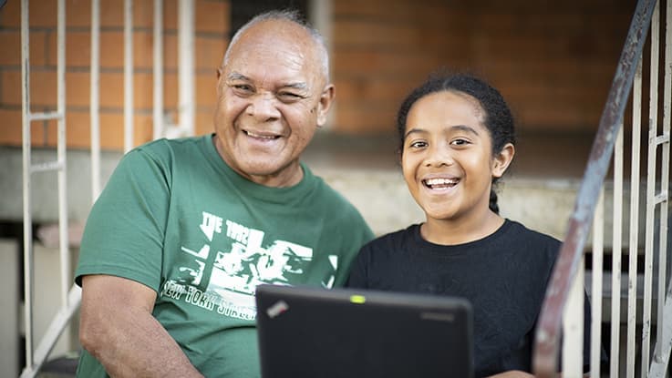 Young boy and his dad sitting on steps using a laptop