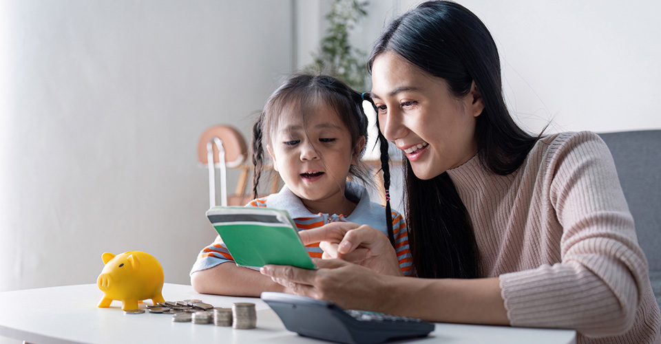 mother and daughter sitting at the coffee table learning about money and saving