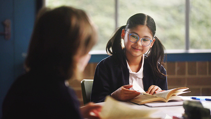 girl wearing glasses reading a book