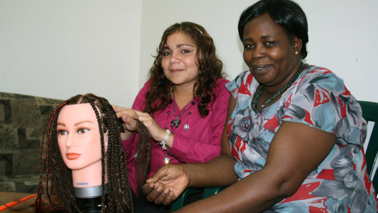 Student learning hair braiding at an African salon