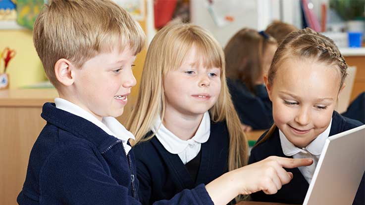 Three primary school students looking at computer