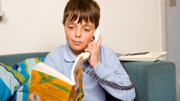 Boy sitting on couch reading over the phone