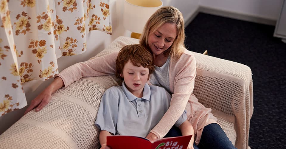 boy reading with his mum on lounge