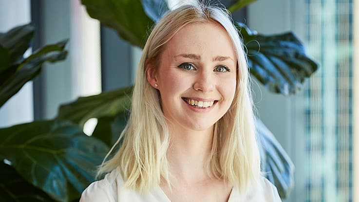 april wearing a white shirt in front of a ficus