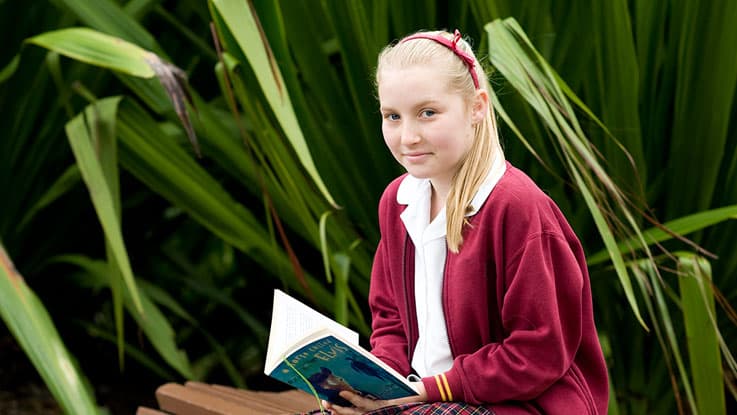 Learning for Life student Melanie reading her book outside